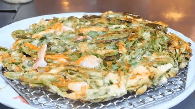 Cooking fresh vegetable seafood and green onion pancake on griddle