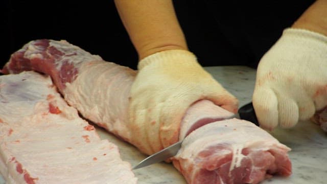 Cutting raw pork on a marble countertop