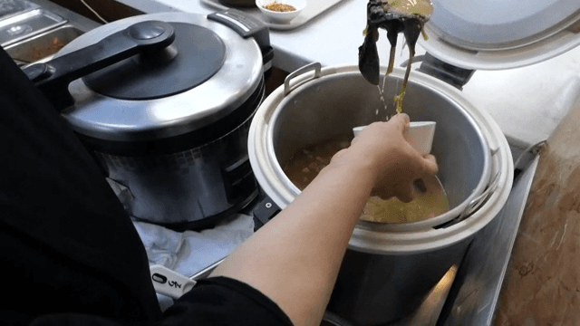 Ladling spinach soybean paste soup into a bowl from a cooker