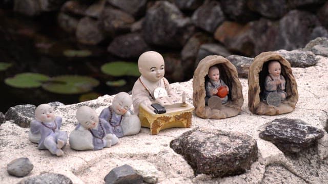 Statues of monks and boy monks on stones near a pond