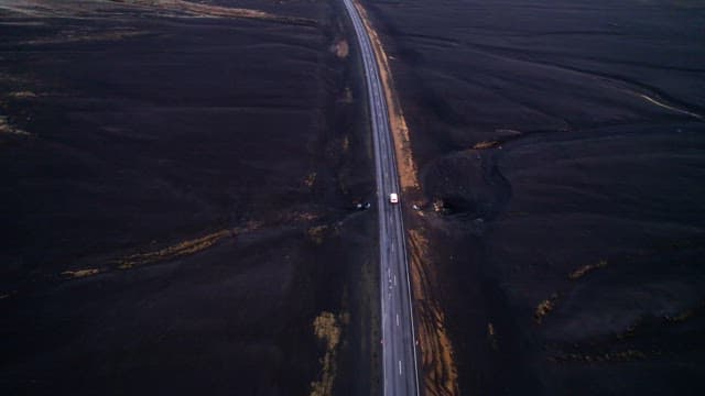 Car traveling on a road through a vast barren landscape