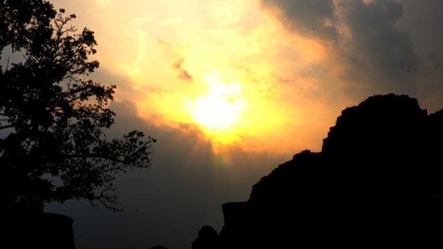 Sunset behind clouds over mountain silhouette