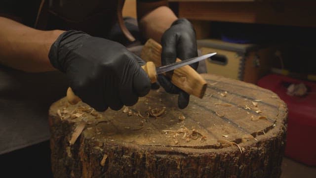 Person carving wood with an knife indoors