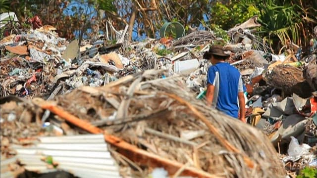 Man walking amidst piles of garbage