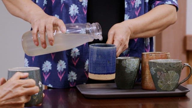 Pouring tea into ceramic mugs indoors