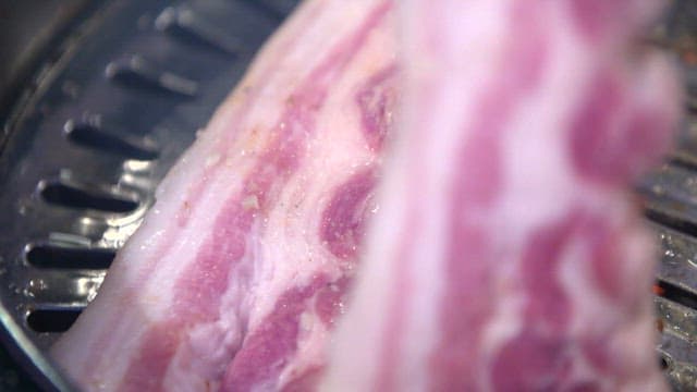 Grilling pork belly on a metal grill