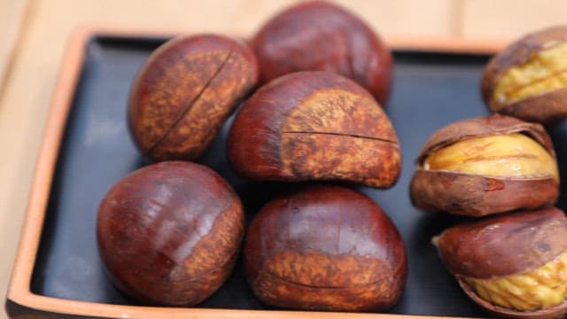 Roasted chestnuts on a black tray