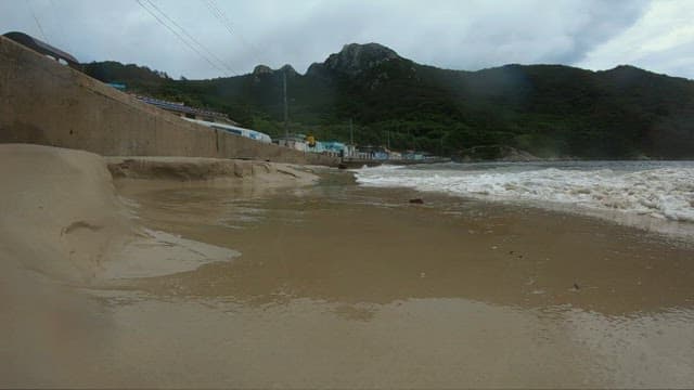 Waves crashing onto a quiet sandy beach in a coastal town