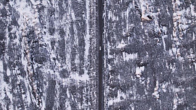 Car driving on a snowy road in a vast landscape