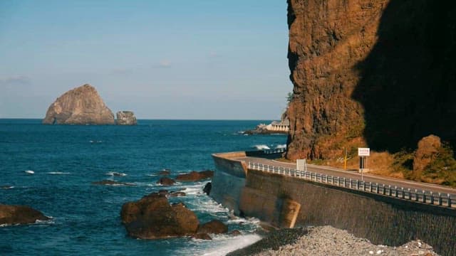 Coastal road stretching beneath sheer cliffs