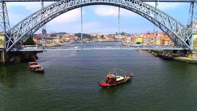 Aerial view of a boat under a scenic bridge, Dom Luis I Bridge