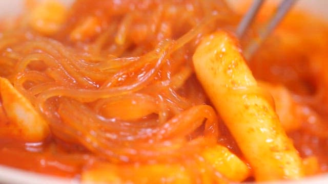 Spicy tteokbokki with noodles being stirred