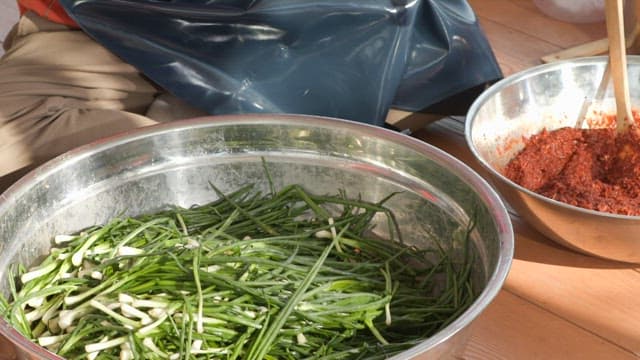 Preparing kimchi with fresh green onions in a metal basin
