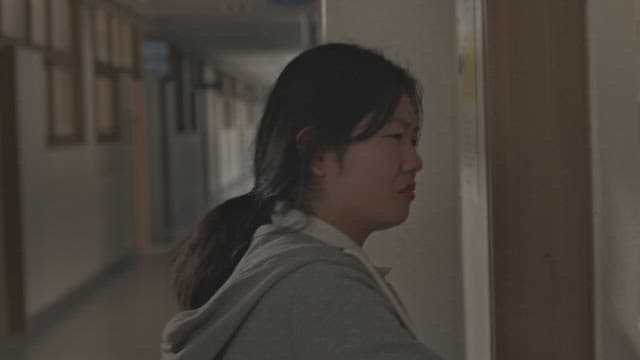 Female student crying while looking at the door in the school hallway