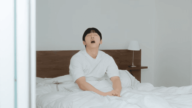 Man waking up and stretching in bed 