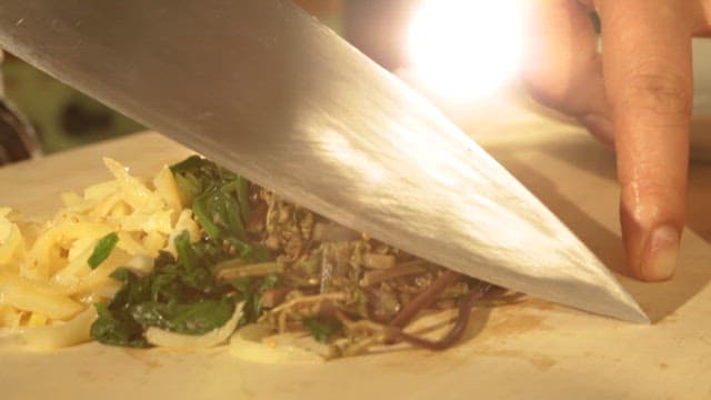 Chopping Various Types of Greens on a Wooden Cutting Board
