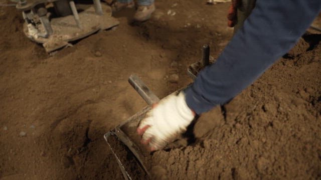 Worker handling soil with tools