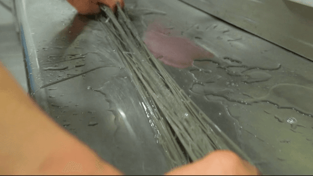 Chef preparing cold buckwheat noodles on a metal surface