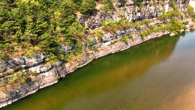 Tranquil river flowing beside rocky cliffs