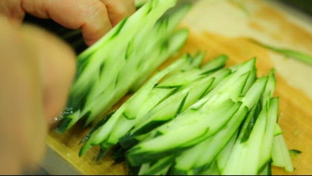 Slicing fresh cucumbers on a wooden cutting board