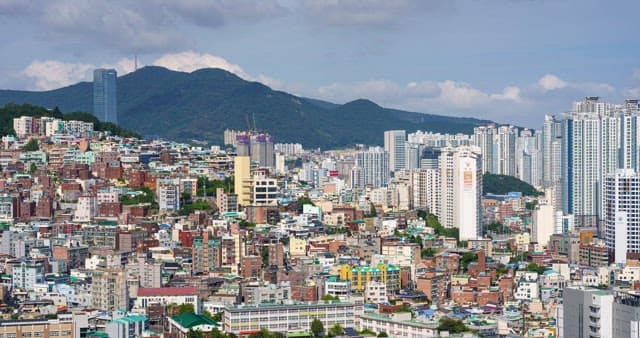Cityscape with densely packed buildings against a mountain backdrop
