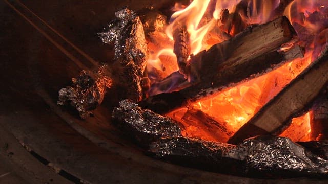 Roasting sweet potatoes over a roaring campfire all night long