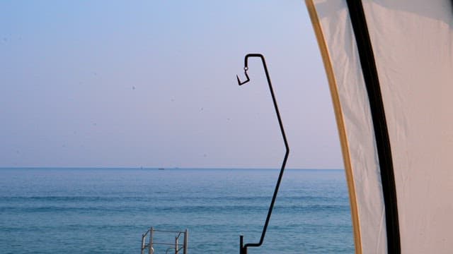 A beautiful seaside view framed by a tent opening in the early morning.