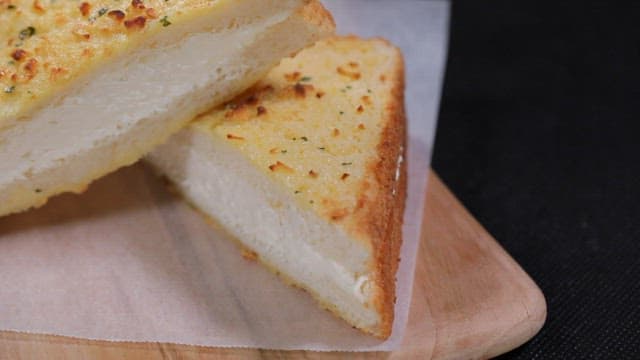 Garlic bread slices filled with cream on a wooden board