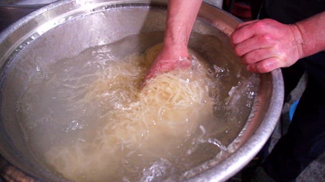 Hand washing noodles in a large pot
