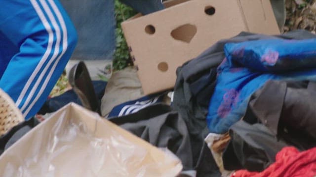 Two people looking for useful items in a clothing bin