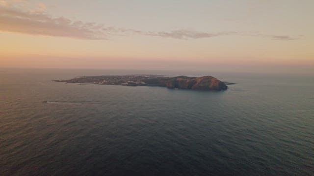 Beautiful island surrounded by calm ocean at sunset